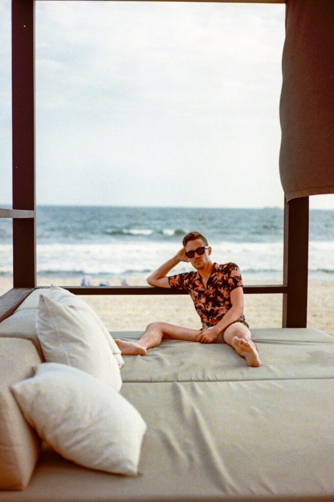 Person relaxing on a beach house lounge with the Atlantic Ocean visible in the background.