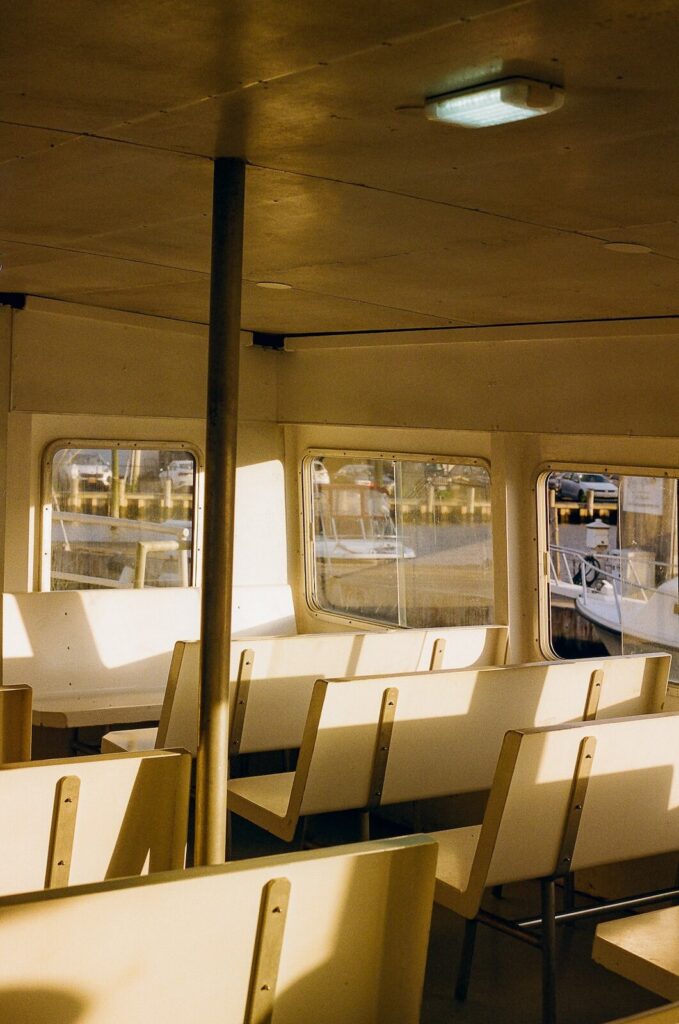Interior of a Fire Island ferry with empty seats glowing in warm sunset light.