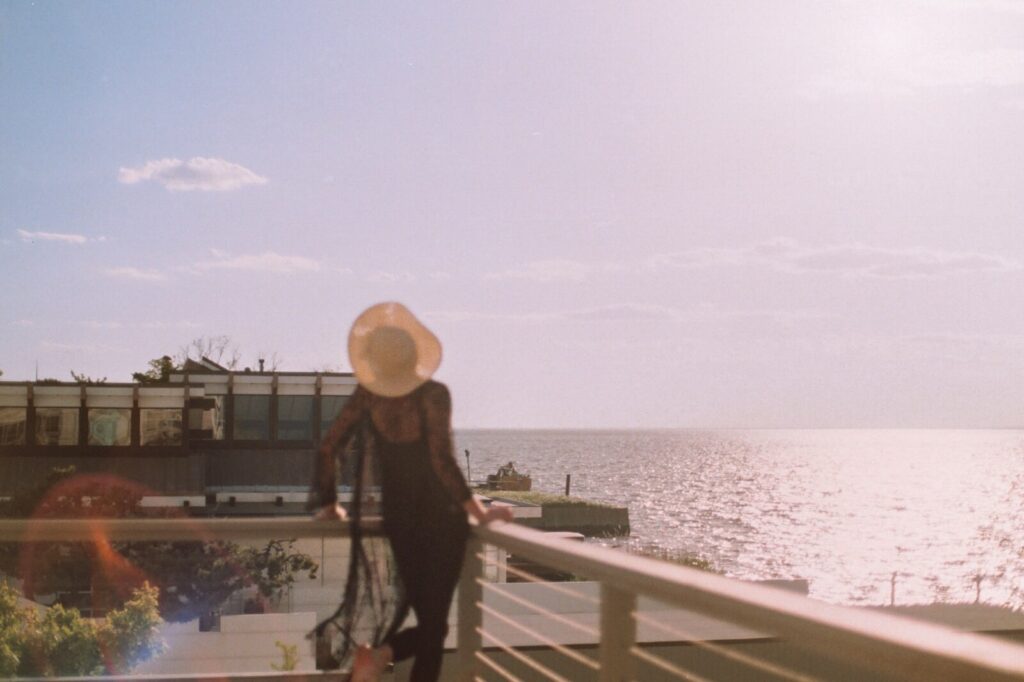 Person standing on a balcony overlooking the ocean in Fire Island Pines during golden hour.