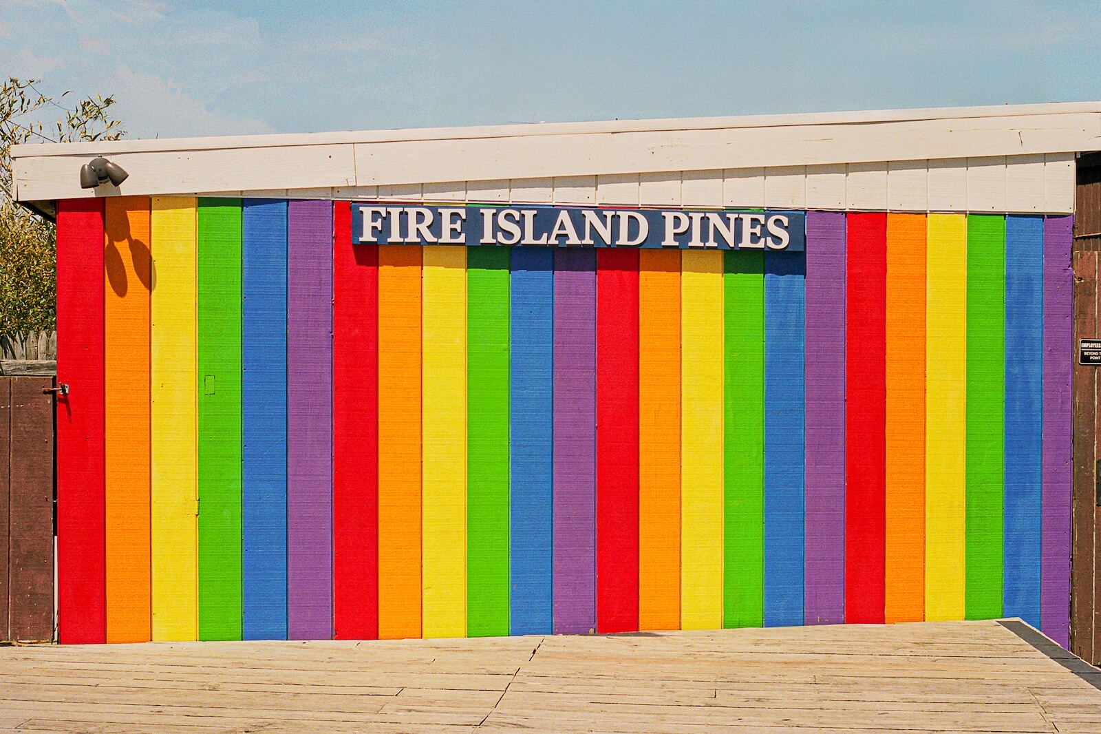 Colorful rainbow wall with Fire Island Pines sign above it.